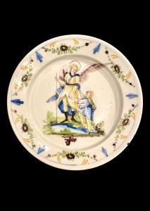 Piatto in maiolica con tesa decorata a festoni e motivi floreali e scena nel cavetto con ‘arcangelo Raffaele e Tobiolo’.Pavia.