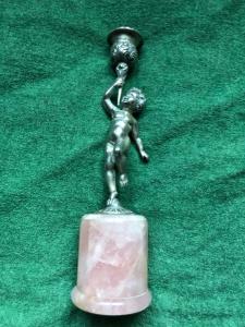 Candelabro de plata con base de cuarzo rosa que representa a un niño desnudo sosteniendo el candelero Italia.
    