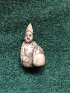 Netsuke de marfil con figura sentada con sombrero, Japón.
    