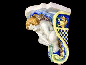 Coppia di mensole in maiolica con  putti e motivi a conchiglia.Manifattura Rubbiani di Sassuolo.