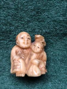 Ivory netsuke 'con figura sentada y niño con rana en la cabeza, Japón.
    