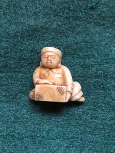 Netsuke de marfil con figura sentada con tronco de madera, Japón.
    