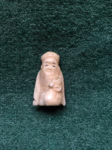 Ivory netsuke 'con personaje sentado con saco en mano, Japón.
    