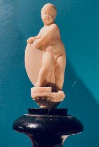 Scultura in avorio raffigurante Putto con scudo, su capitello. 