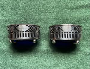 Pareja de saleros de plata perforada con motivos geométricos.
    