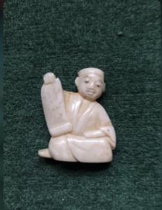 Netsuke de marfil con figura sentada con papiro. Japón.
    
