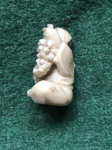 Ivory netsuke 'con carácter sentado con racimo de uvas. Japón
    