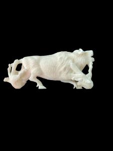 Escultura de marfil que representa un bisonte atacado por dos lobos.