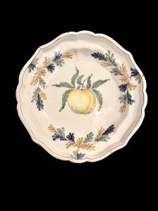 Piatto in maiolica fondo con racemi vegetali sulla tesa e frutto nel cavetto.Pavia.